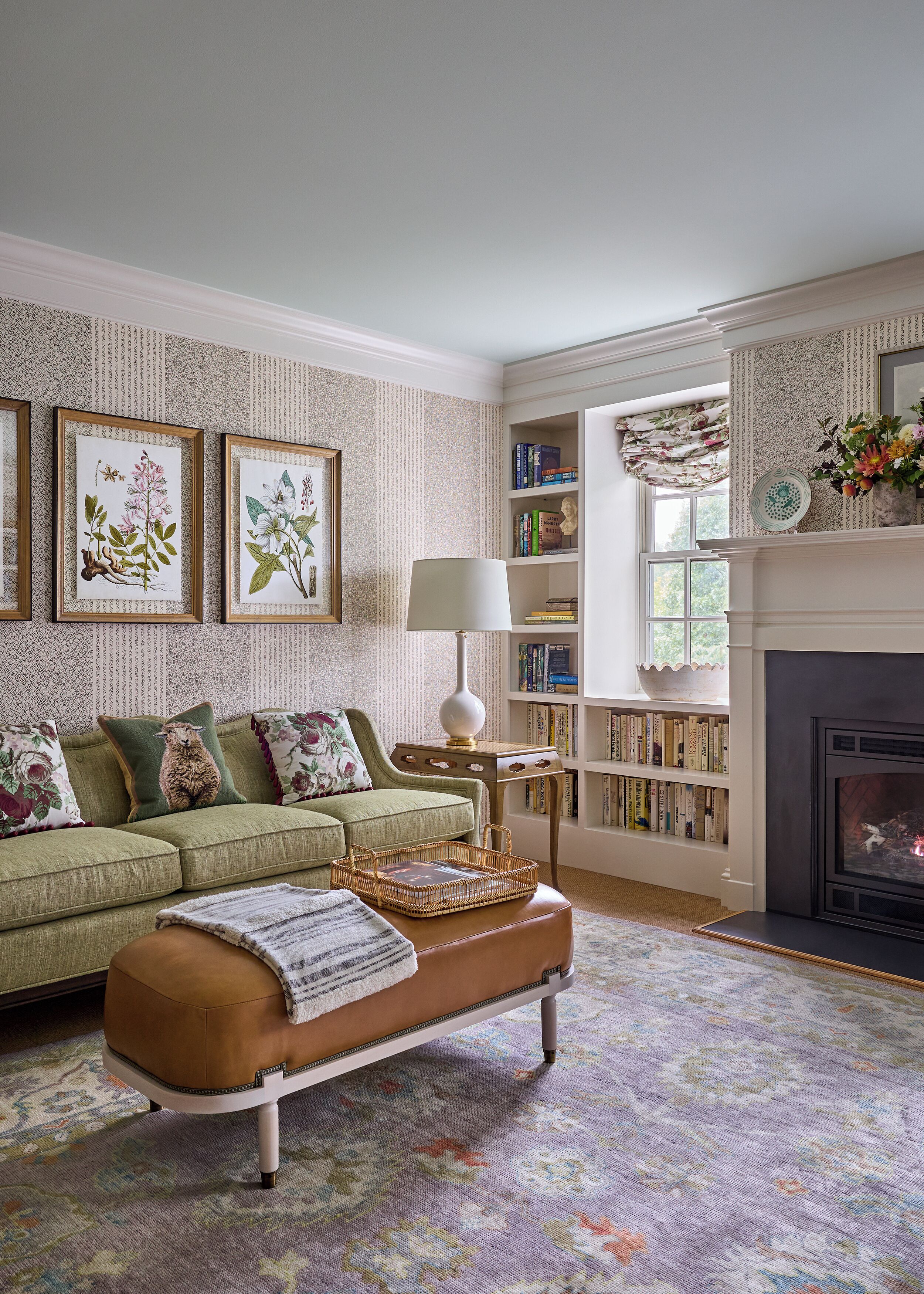 A living room with a green sofa, a patterned rug, a fireplace, and a bookshelf filled with books.