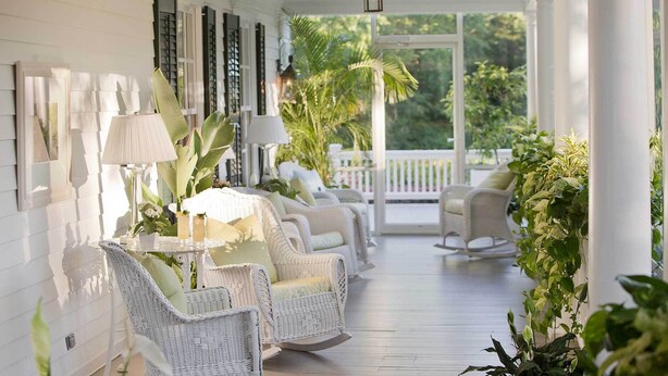 A covered porch with wicker furniture, a table with drinks, and potted plants. - Mayflower Inn & Spa, Auberge Collection (Washington)