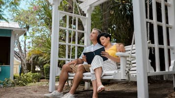 Couples can relax together on a charming outdoor swing set amidst lush greenery.
