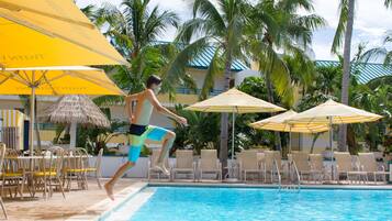 Relax by the pool surrounded by palm trees and lounge chairs.