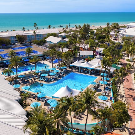 A resort with a central pool, multiple lounge areas, and a beach view.