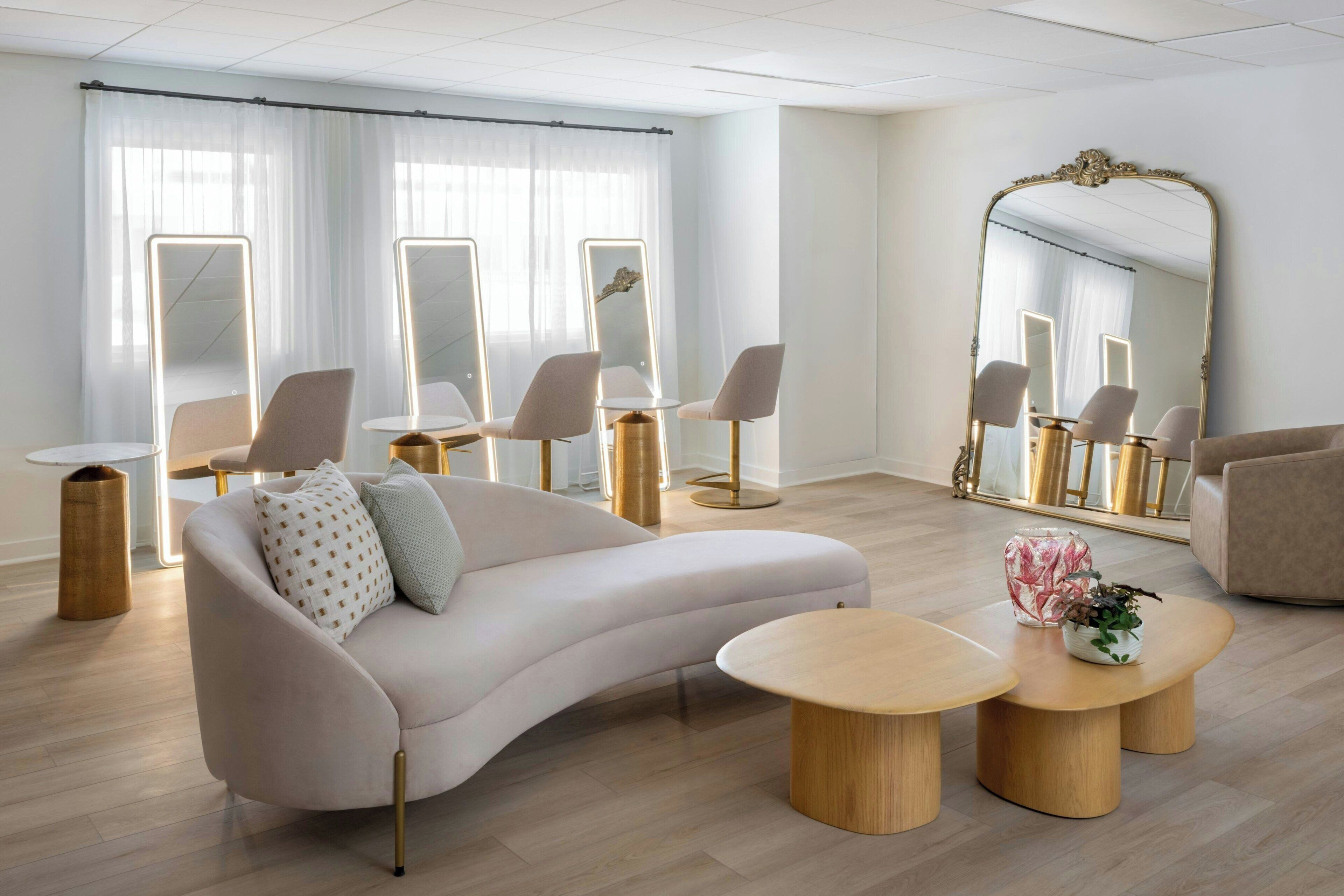 A modern room with a sofa, round tables, and a large mirror.