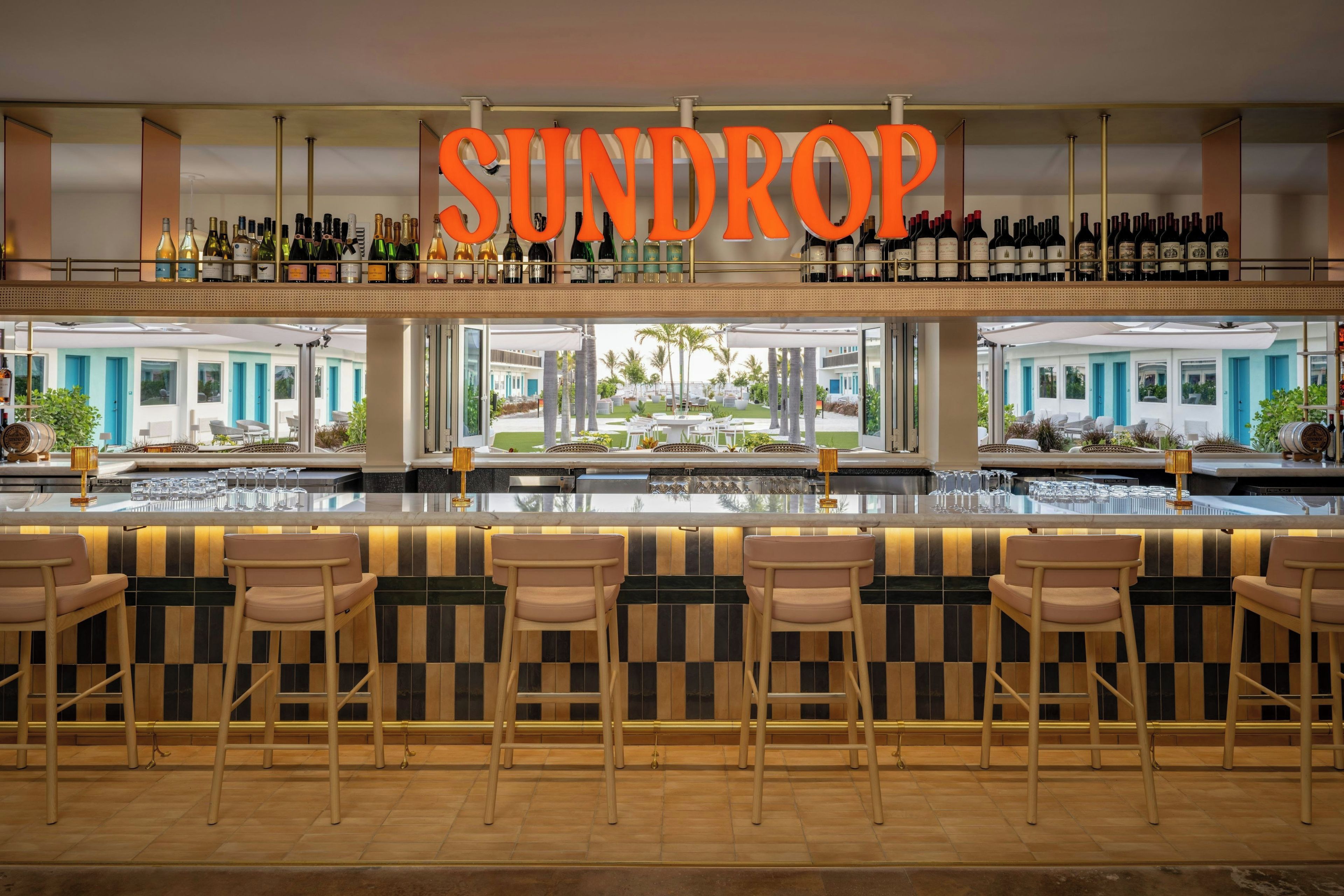 A bar area with a sign reading 'SUNDROP' above a wine rack.