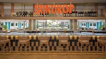 A bar area with a sign reading 'SUNDROP' above a wine rack.