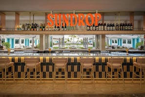 A bar area with a sign reading 'SUNDROP' above a wine rack. - The Luce, St. Pete Beach, a Tribute Portfolio Hotel (St. Pete Beach)