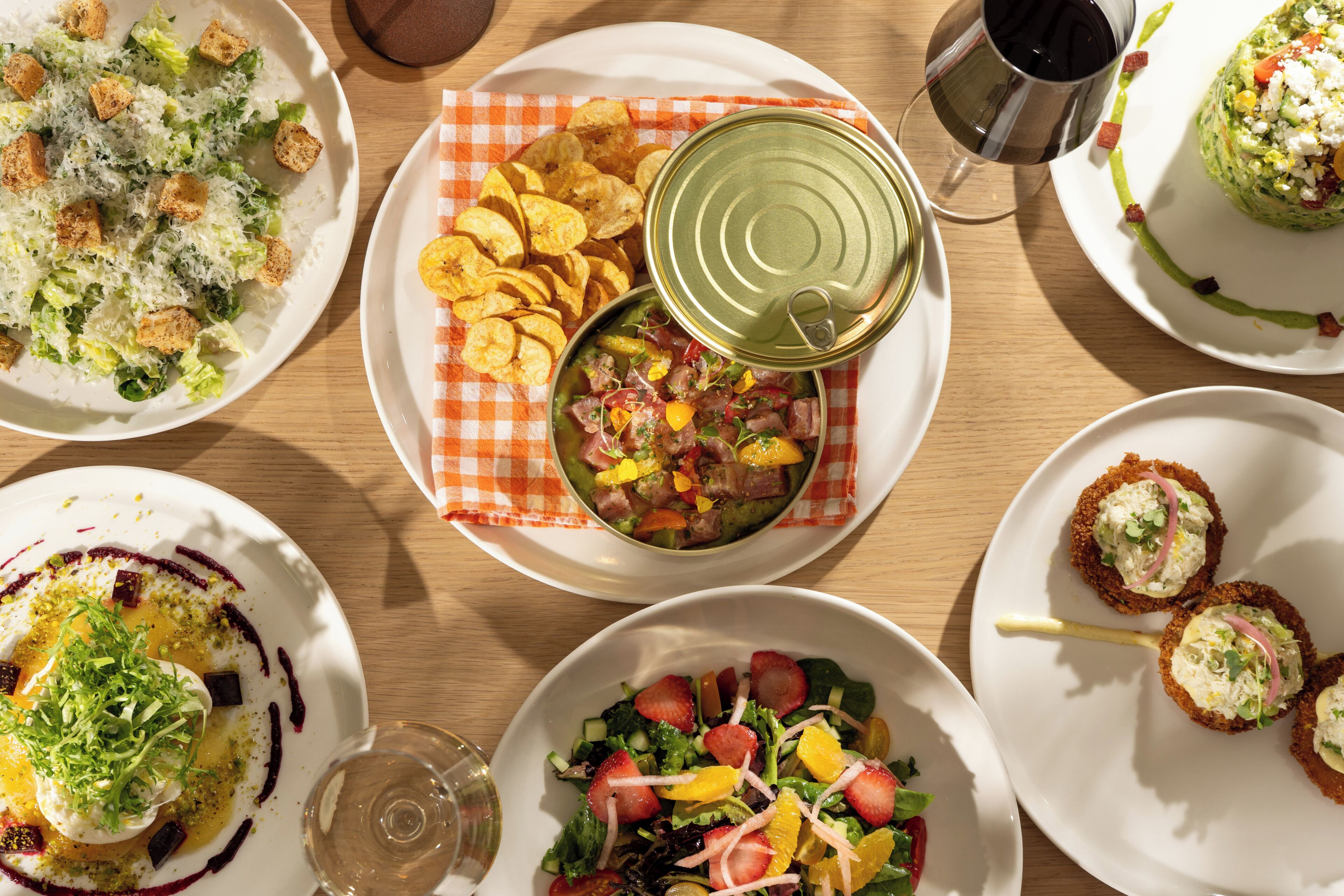 Variedad de platos sobre una mesa de madera, incluyendo ensaladas, un bol de sopa y un plato de papas fritas.