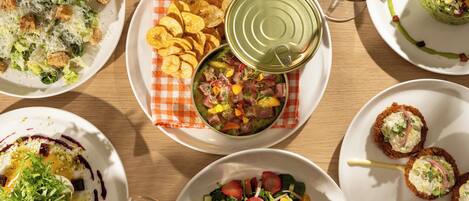 Variedad de platos sobre una mesa de madera, incluyendo ensaladas, un bol de sopa y un plato de papas fritas.