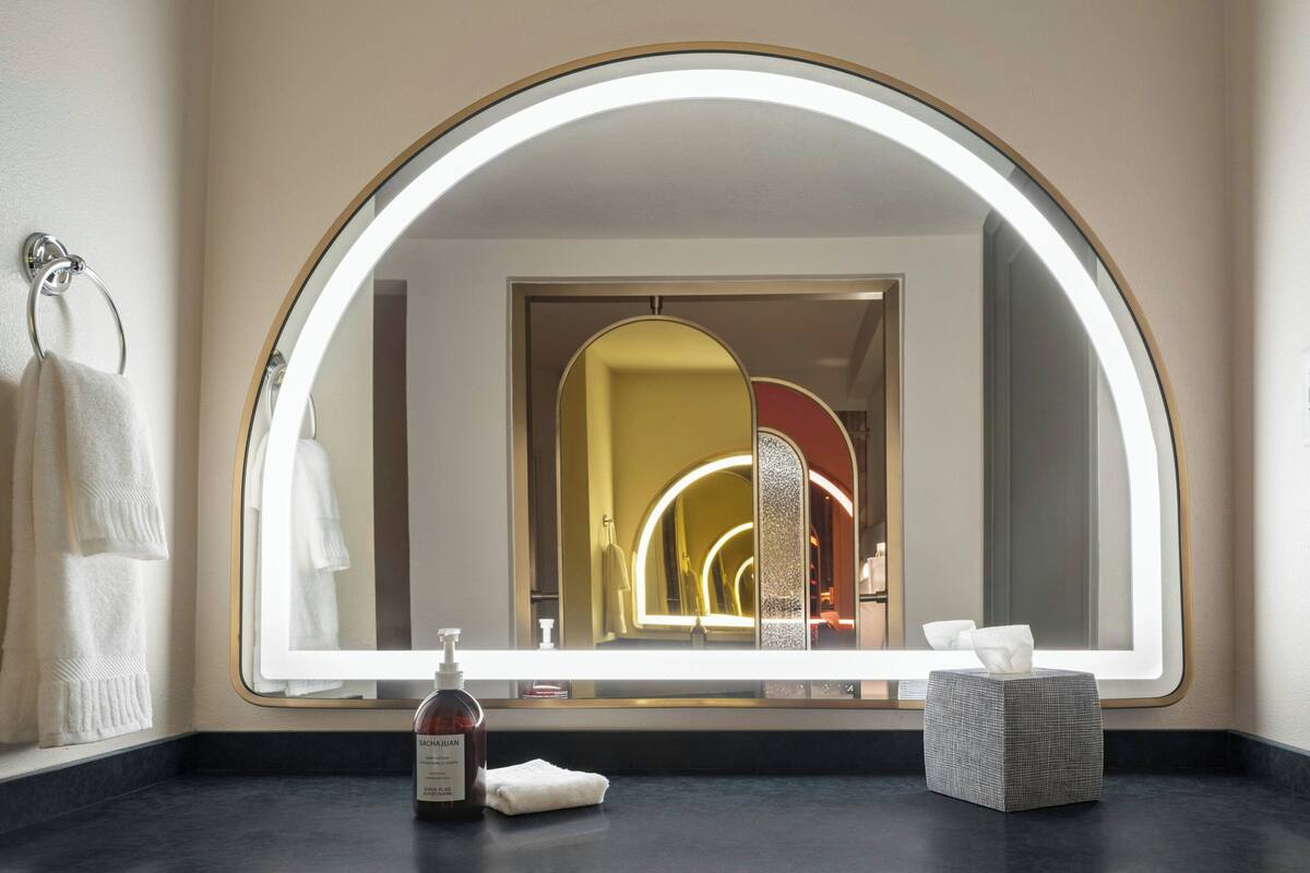 A bathroom with a large mirror, a towel rack, a soap dispenser, and a tissue box.