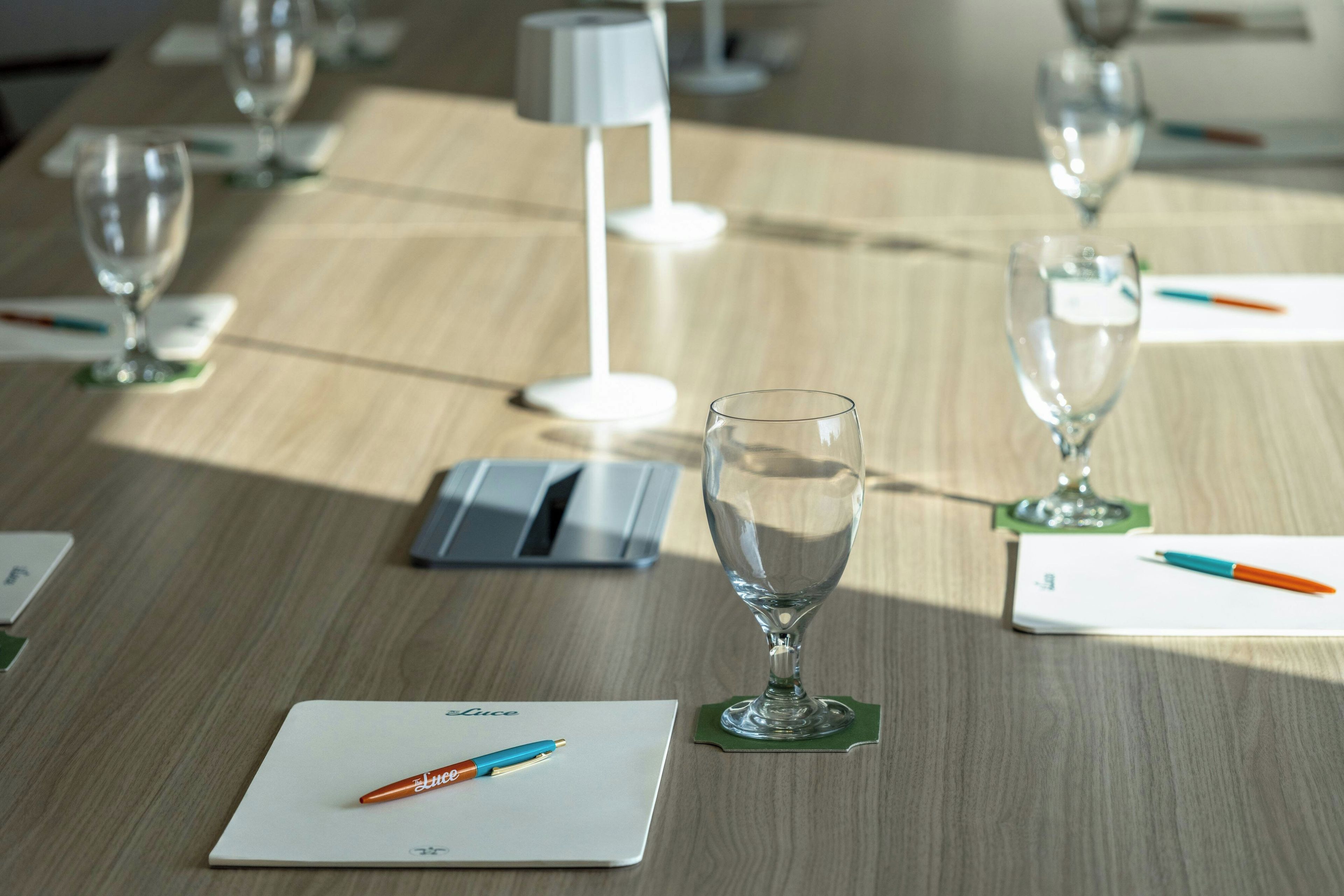 A table with a laptop, a pen, and a glass on a coaster.
