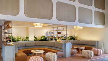 A modern lounge area with seating, tables, and decorative plants.