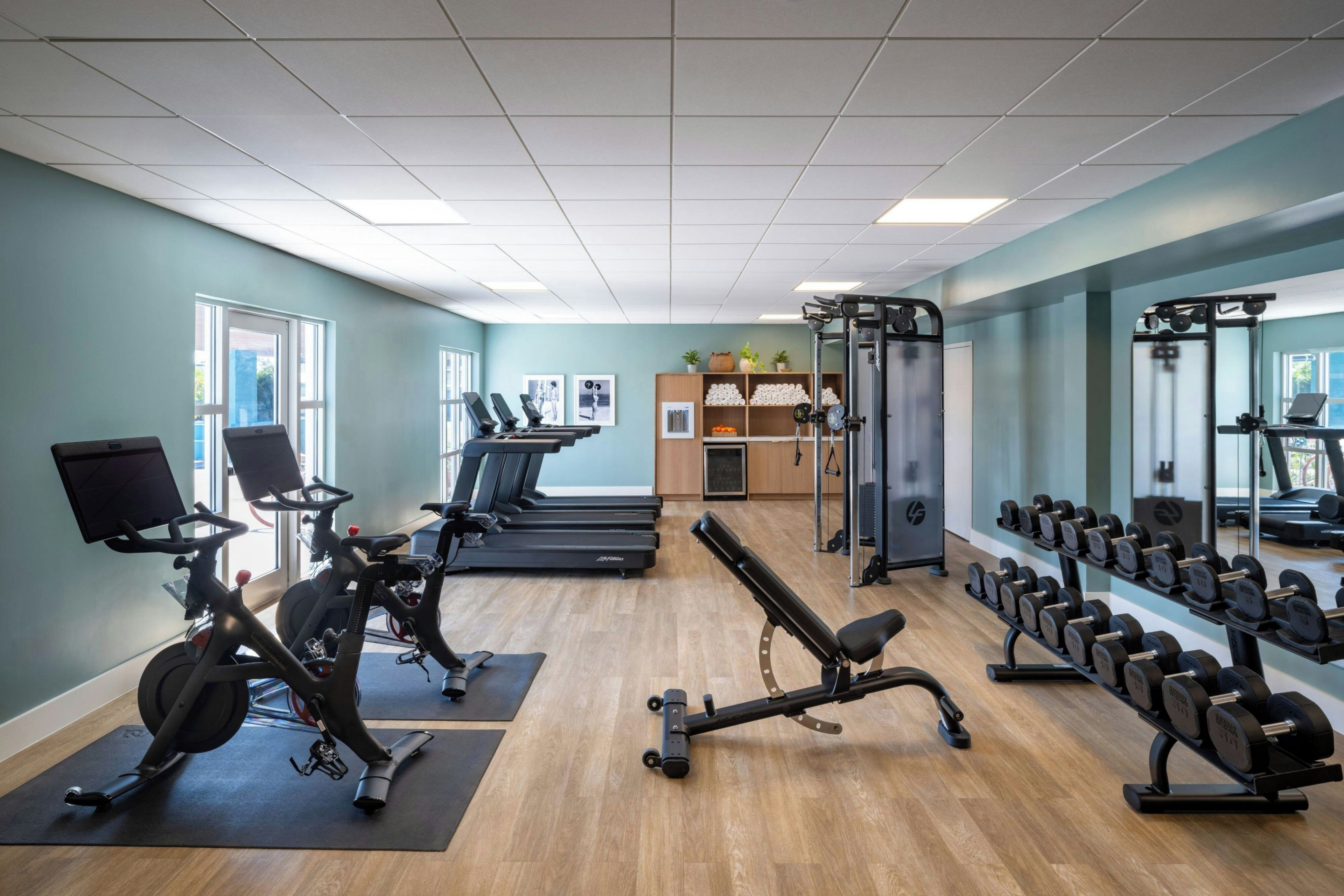 Un gimnasio con equipo de ejercicio, cintas de correr y una banca para pesas.
