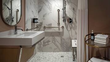 Un baño moderno con lavabo, espejo, ducha e inodoro.