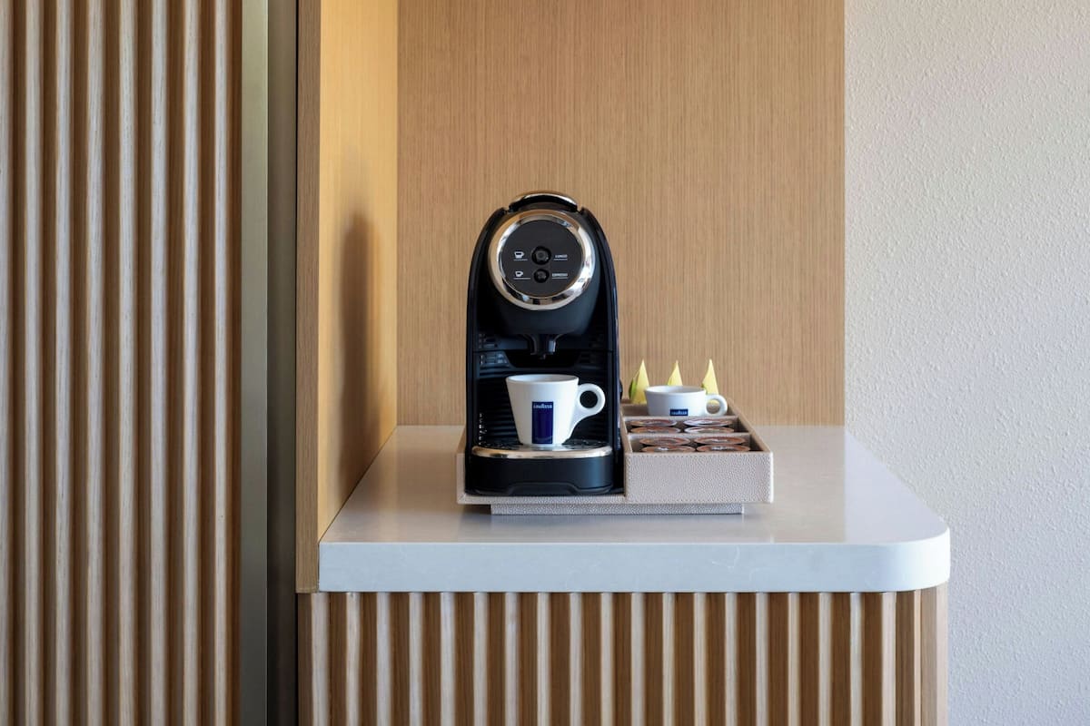 A coffee machine on a white countertop with a wooden panel background.