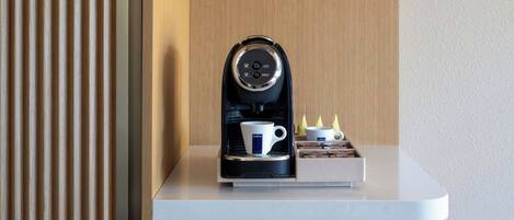 A coffee machine on a white countertop with a wooden panel background.