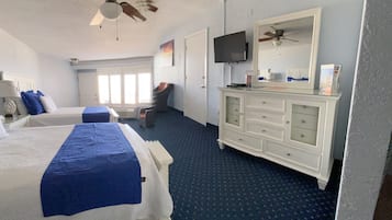 Une chambre d’hôtel avec deux lits, une commode, un téléviseur et un ventilateur de plafond.