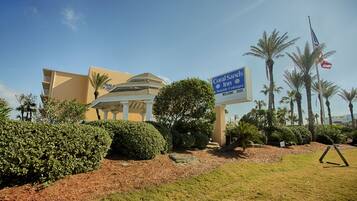 A hotel with a sign for Coral Sands Inn & Seaside Cottages, surrounded by palm trees and a clear sky.