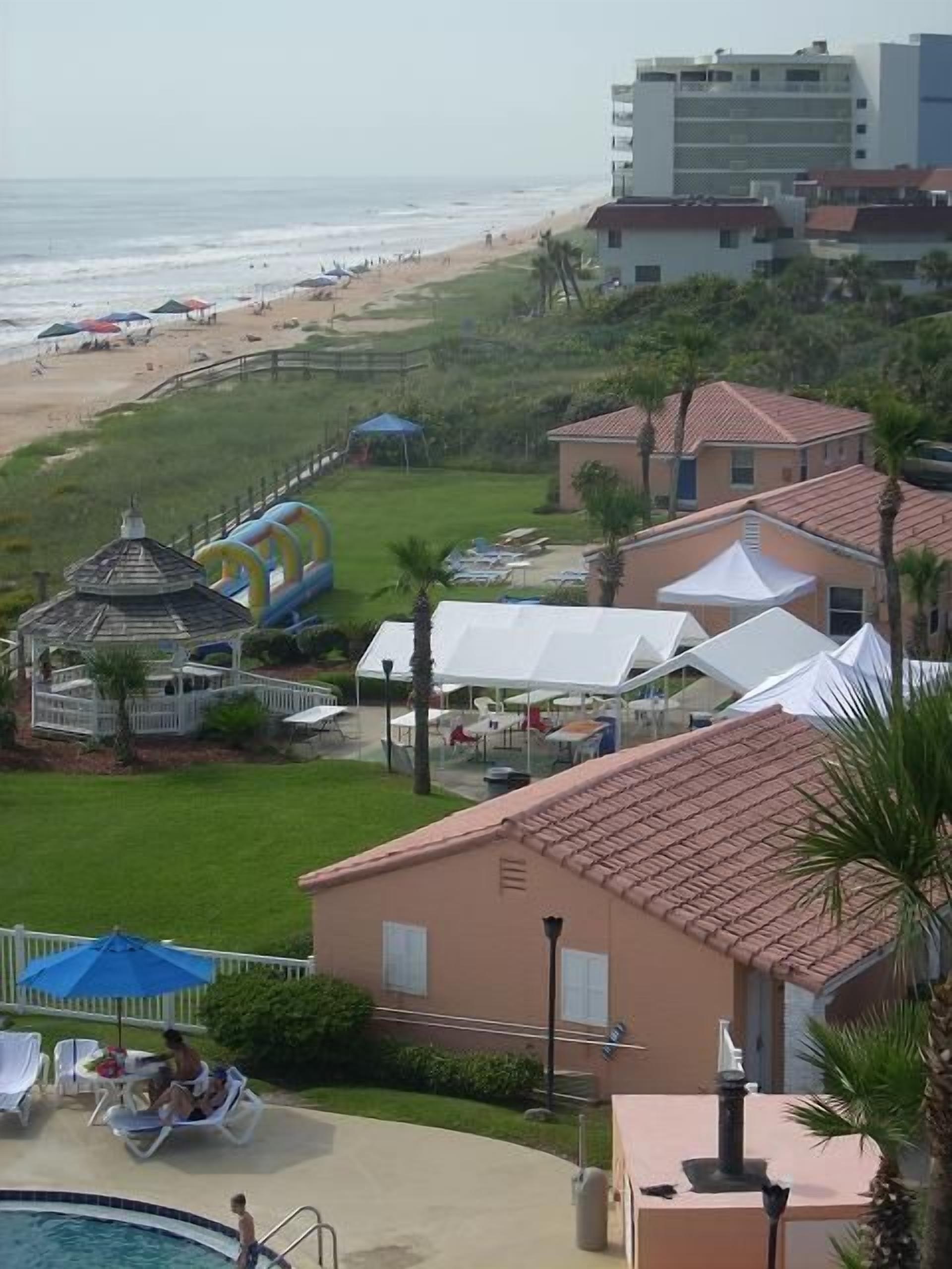 Un resort con piscina, vista a la playa y zona de comedor al aire libre.