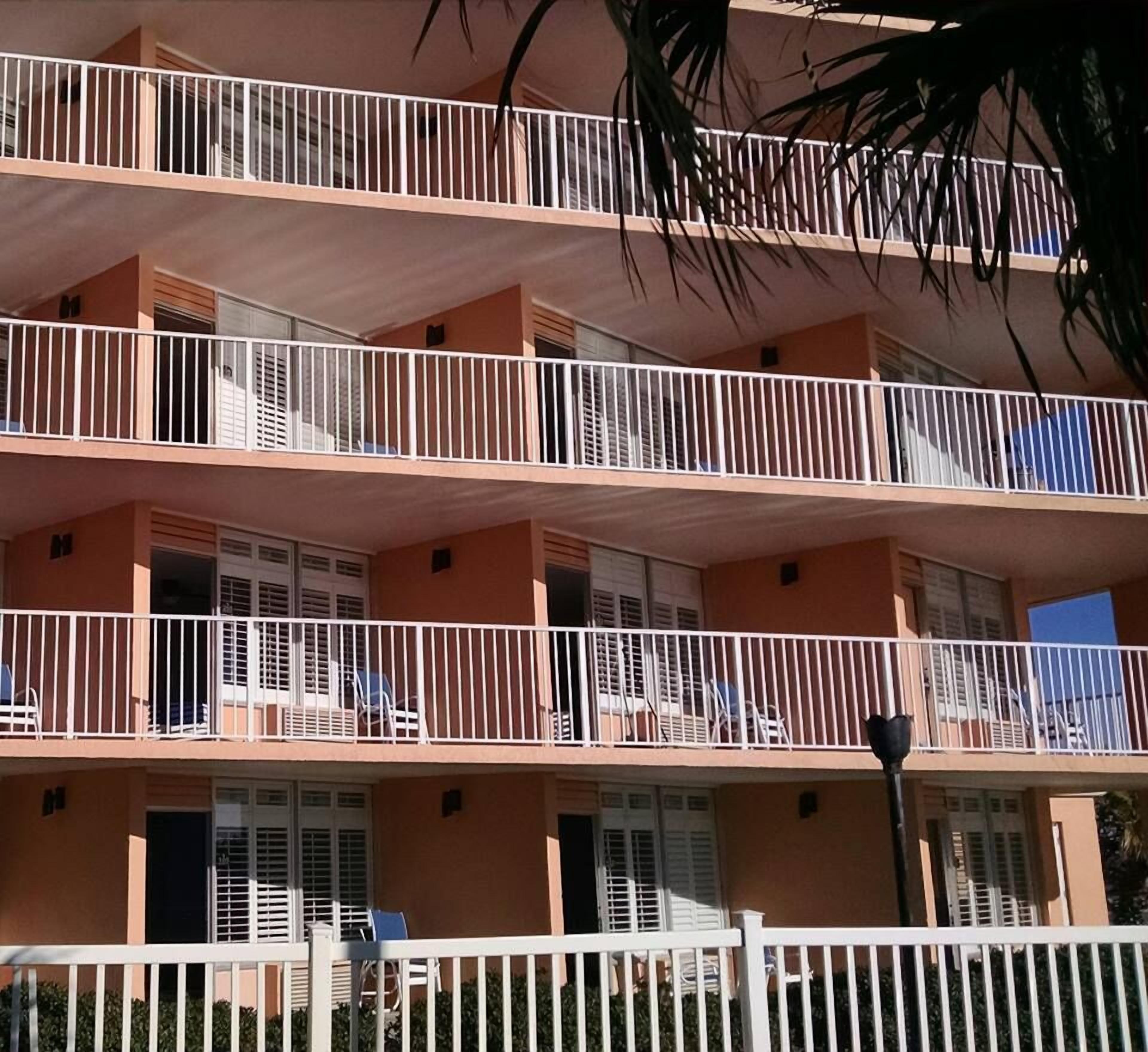 A multi-story building with balconies, each with a white railing.