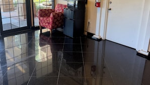 A lobby with a tiled floor, a framed welcome sign, a fire extinguisher, and a door. - Economy Inn Jax-OP (Jacksonville)