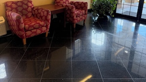 A lobby with a tiled floor, a framed picture on the wall, and a potted plant. - Economy Inn Jax-OP (Jacksonville)