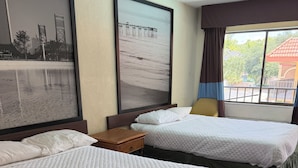 A hotel room with two beds, a framed picture of a pier, a window with curtains, and a small wooden nightstand. - Economy Inn Jax-OP (Jacksonville)