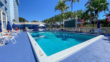 Una piscina al aire libre, sombrillas, sillones reclinables de piscina