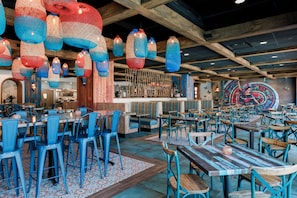A restaurant with blue chairs, wooden tables, and hanging blue and red lanterns. - Westgate Towers Resort (Kissimmee)