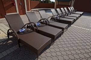 A poolside area with wicker lounge chairs and a hexagonal tiled floor.