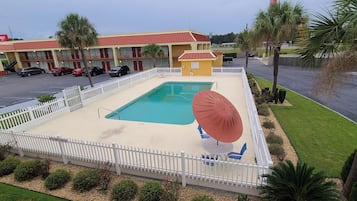 A motel with a swimming pool, a fenced patio area, and a parking lot.
