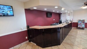 A modern kitchen with a dark island, recessed lighting, and a view of the outside through large windows. - Red Roof Inn Tifton (Tifton)