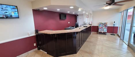 Una cocina moderna con una isla oscura, iluminación empotrada y vistas al exterior a través de amplias ventanas.
