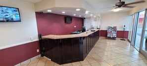 A modern kitchen with a dark island, recessed lighting, and a view of the outside through large windows. - Red Roof Inn Tifton (Tifton)
