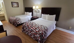 A hotel room with two beds, a nightstand, a lamp, and a painting on the wall. - Red Roof Inn Tifton (Tifton)