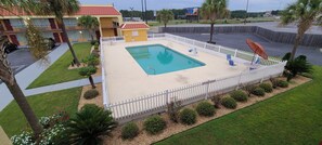 A swimming pool surrounded by a white fence, with a building in the background. - Red Roof Inn Tifton (Tifton)