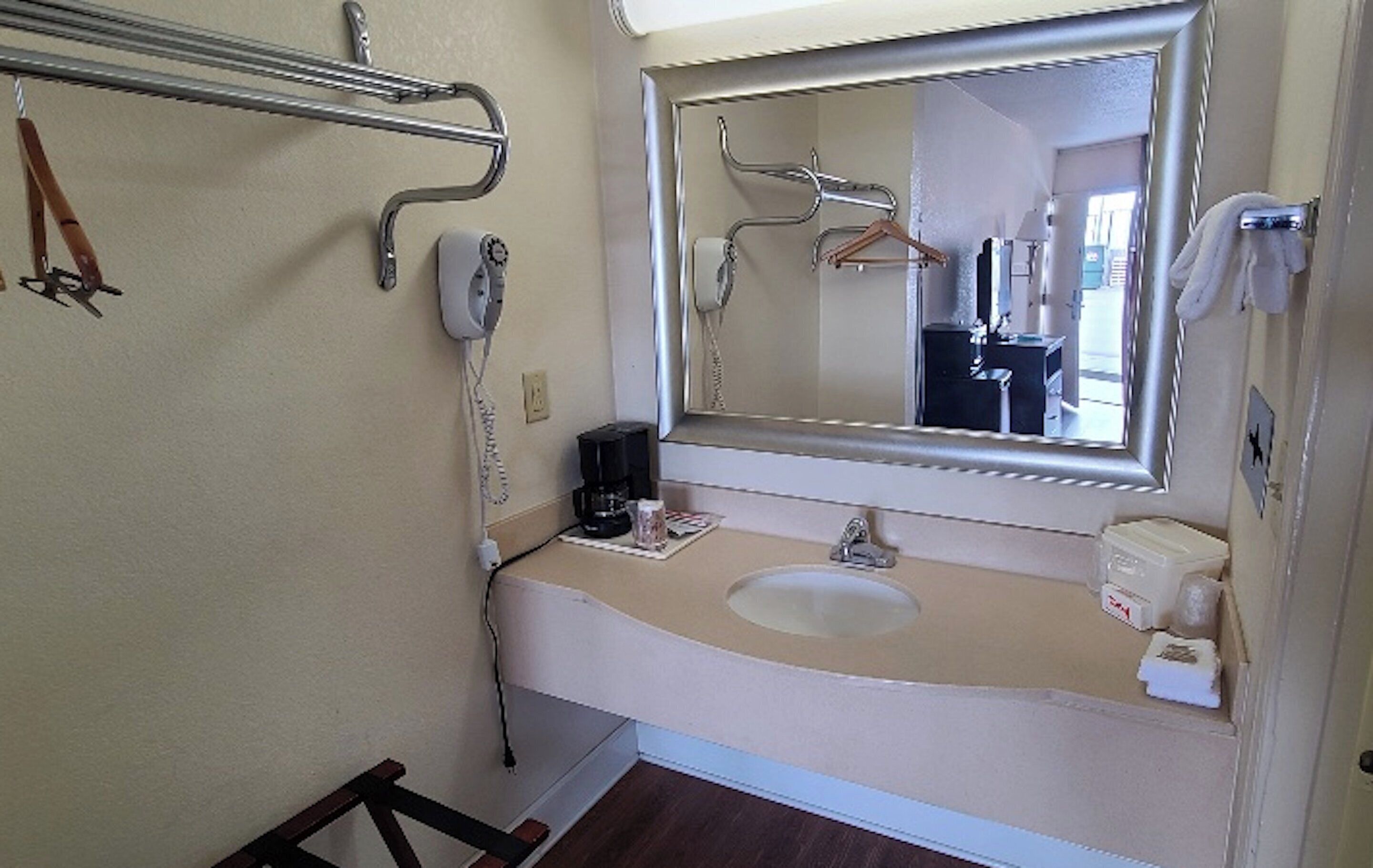 Een badkamer met een wastafel, spiegel, handdoekhouder en een haardroger.