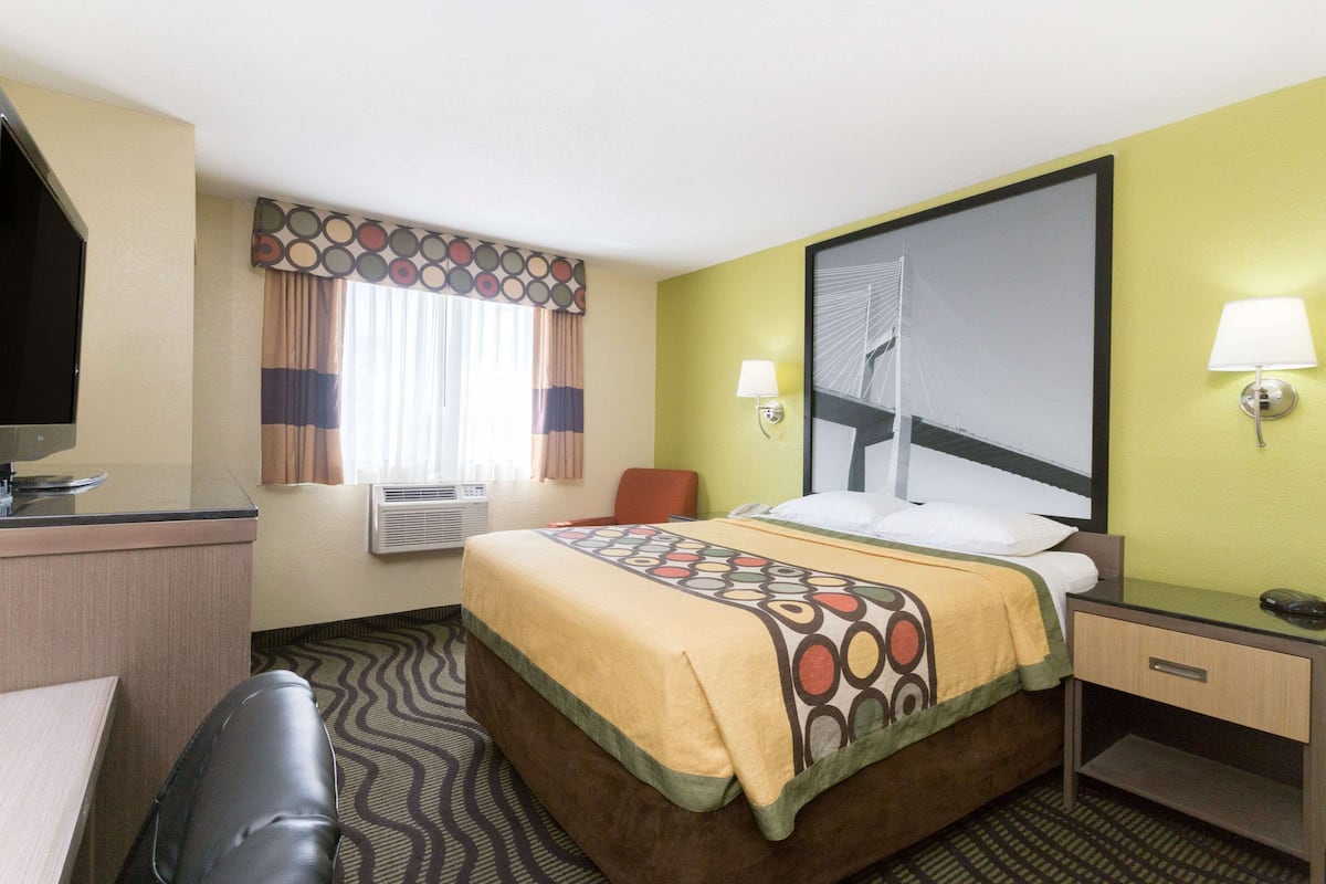 A hotel room with a bed, desk, chair, and two bedside lamps.