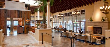 A spacious lobby with a high ceiling, large windows, and a fireplace.