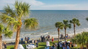 A coastal event with tables and chairs set up on grass, palm trees, and a view of the sea. - The King and Prince Beach & Golf Resort (St. Simons Island)