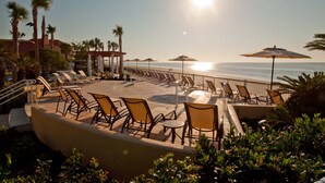 A sunlit outdoor seating area with chairs and umbrellas overlooking the beach. - The King and Prince Beach & Golf Resort (St. Simons Island)