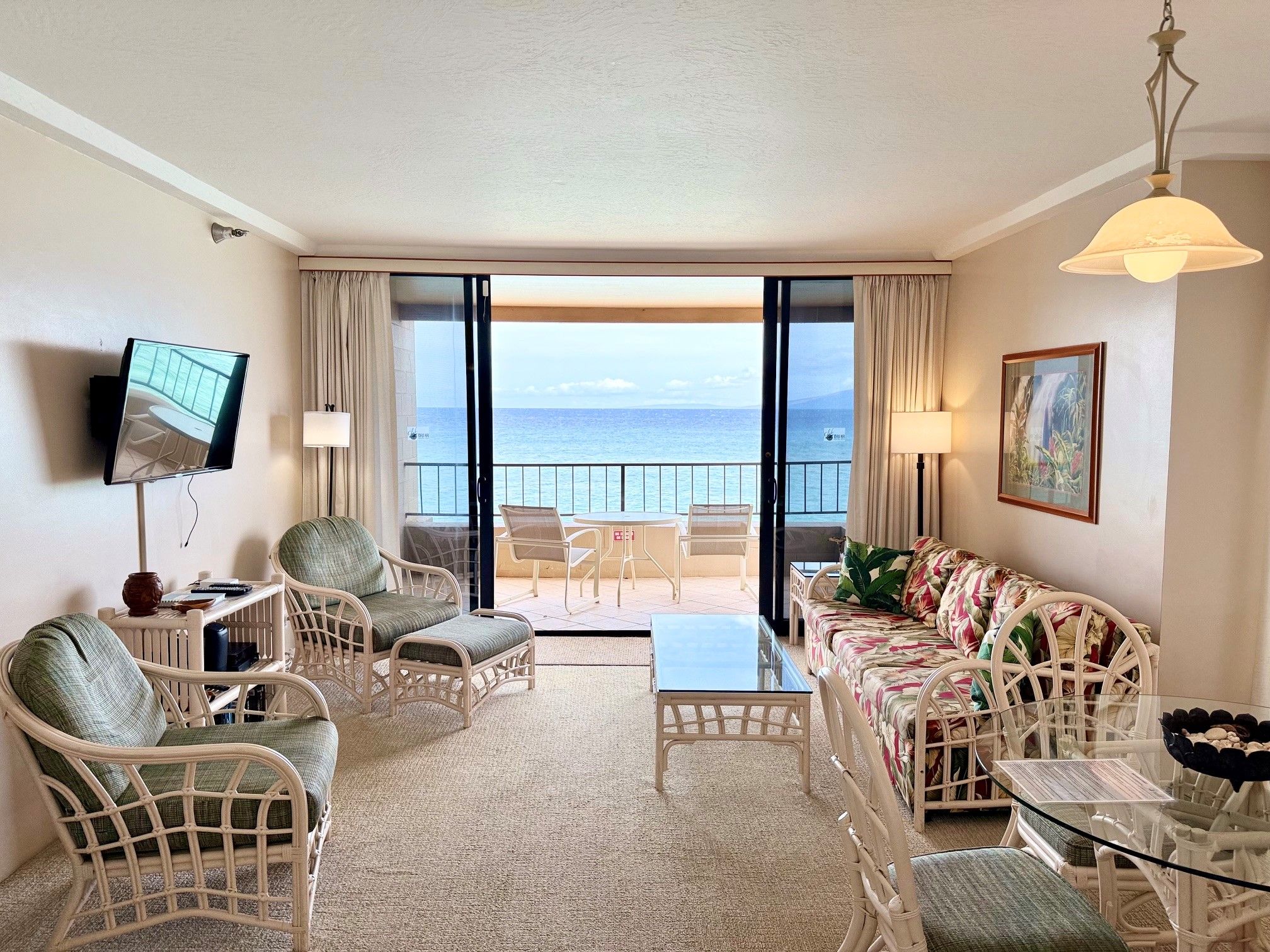 A hotel room with a balcony, a television, a sofa, and a dining table.