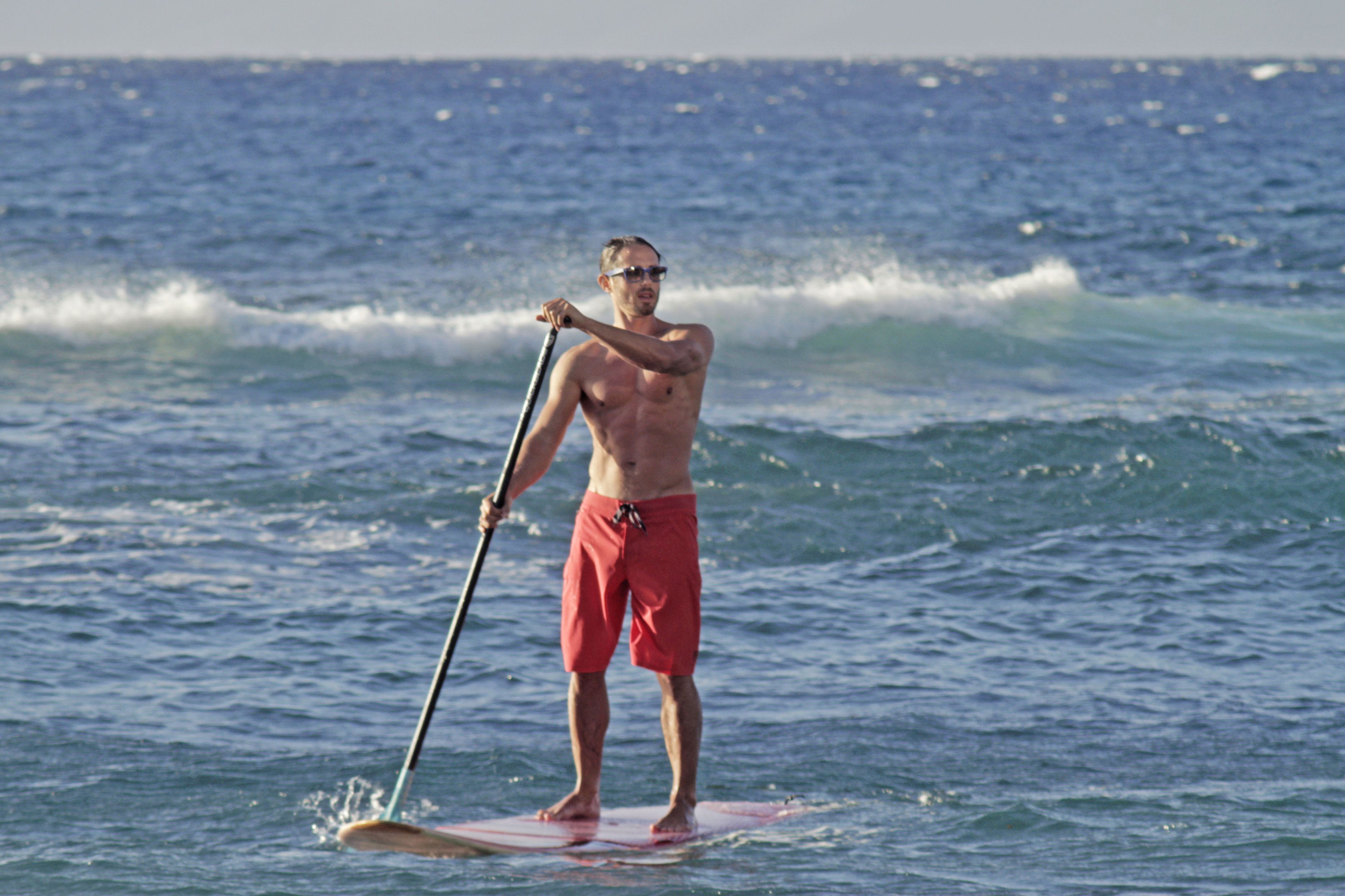 Une personne debout sur une planche de paddle, au milieu de l’océan.