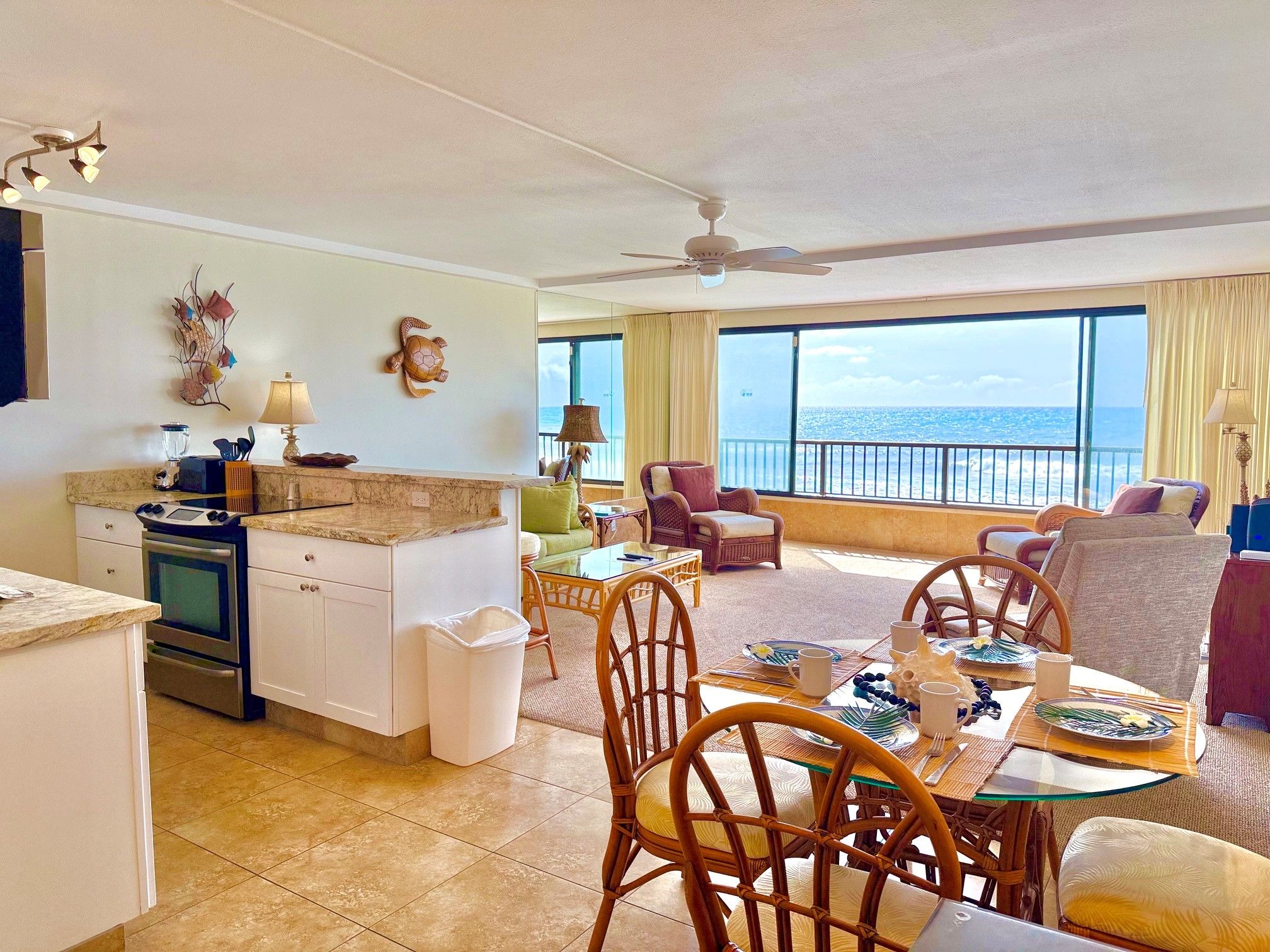 A spacious living area with a balcony overlooking the sea, a kitchen with modern appliances, and a dining area set for a meal.