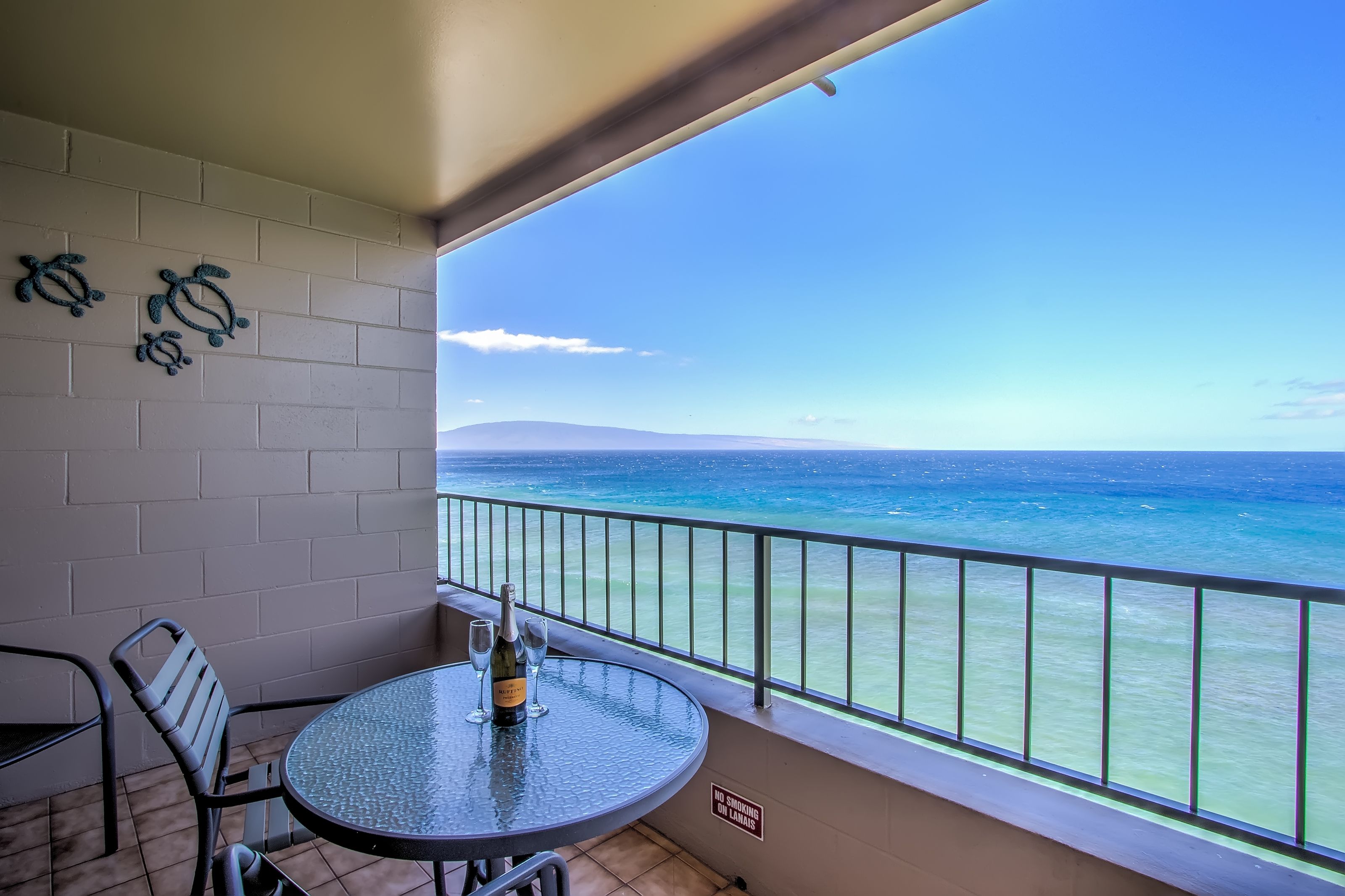 Un balcon avec une table, des chaises et une bouteille de vin.