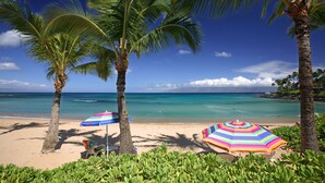 A beach with palm trees, a clear blue sky, and a calm sea. - The Mauian - Boutique Beach Studios on Napili Bay (Lahaina)