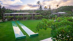 A courtyard with a long reflective pool, surrounded by lush greenery and palm trees. - The Mauian - Boutique Beach Studios on Napili Bay (Lahaina)