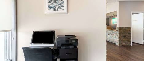 A reception desk with a computer, printer, and a framed artwork on the wall.