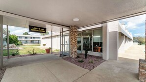 A building entrance with a sign for lobby and meeting rooms, a stone pillar, and a glass door.