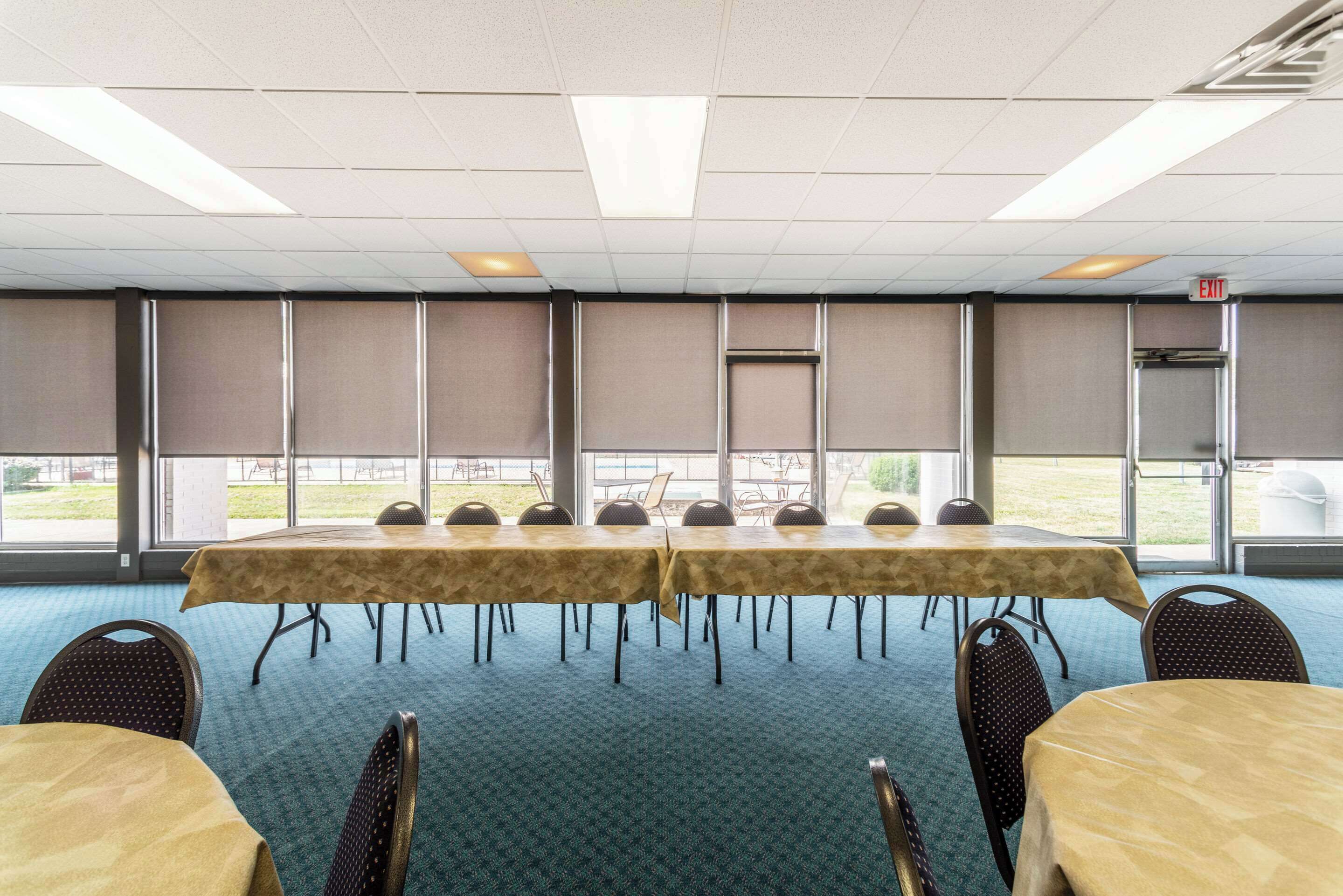 A conference room with a long table and chairs, large windows, and a carpeted floor.