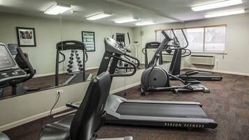 Un gimnasio con cintas de correr, elípticas y una banca de pesas.