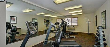 A gym with treadmills, elliptical machines, and a weight rack.